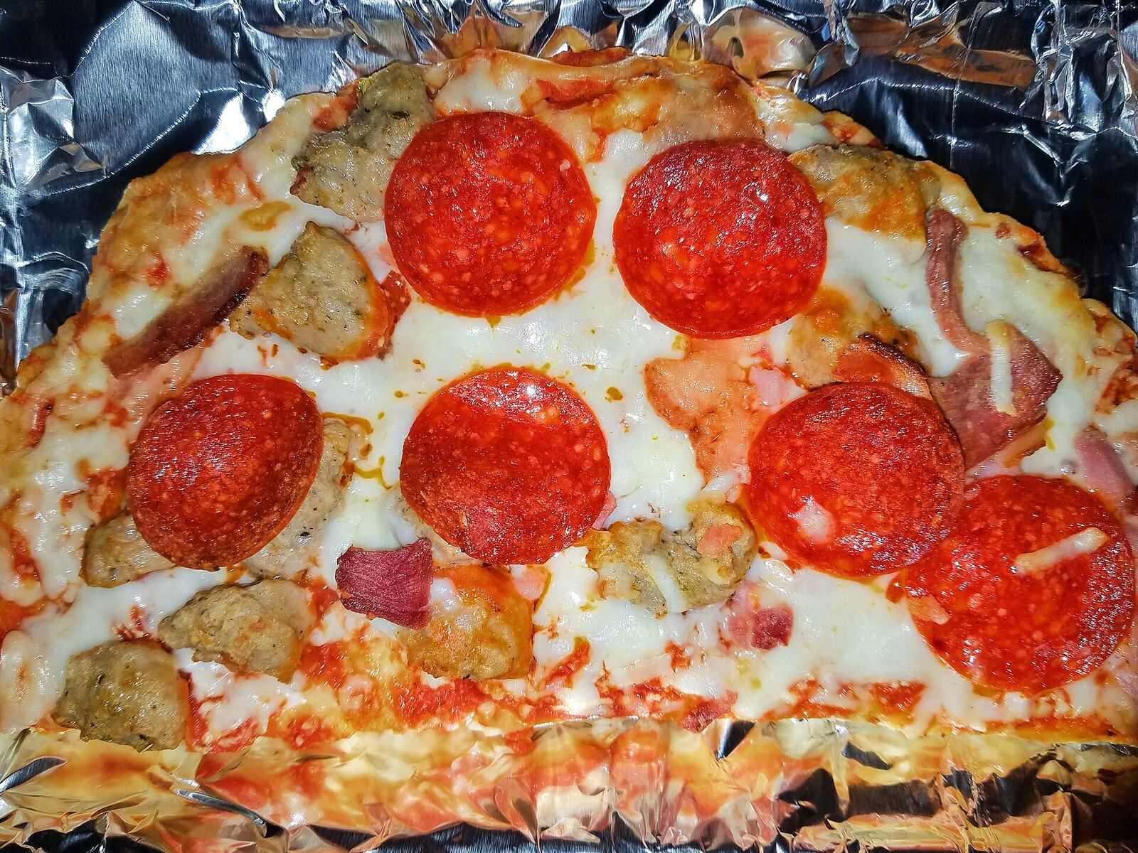 Close-up of large pepperoni slices on bubbling melted cheese