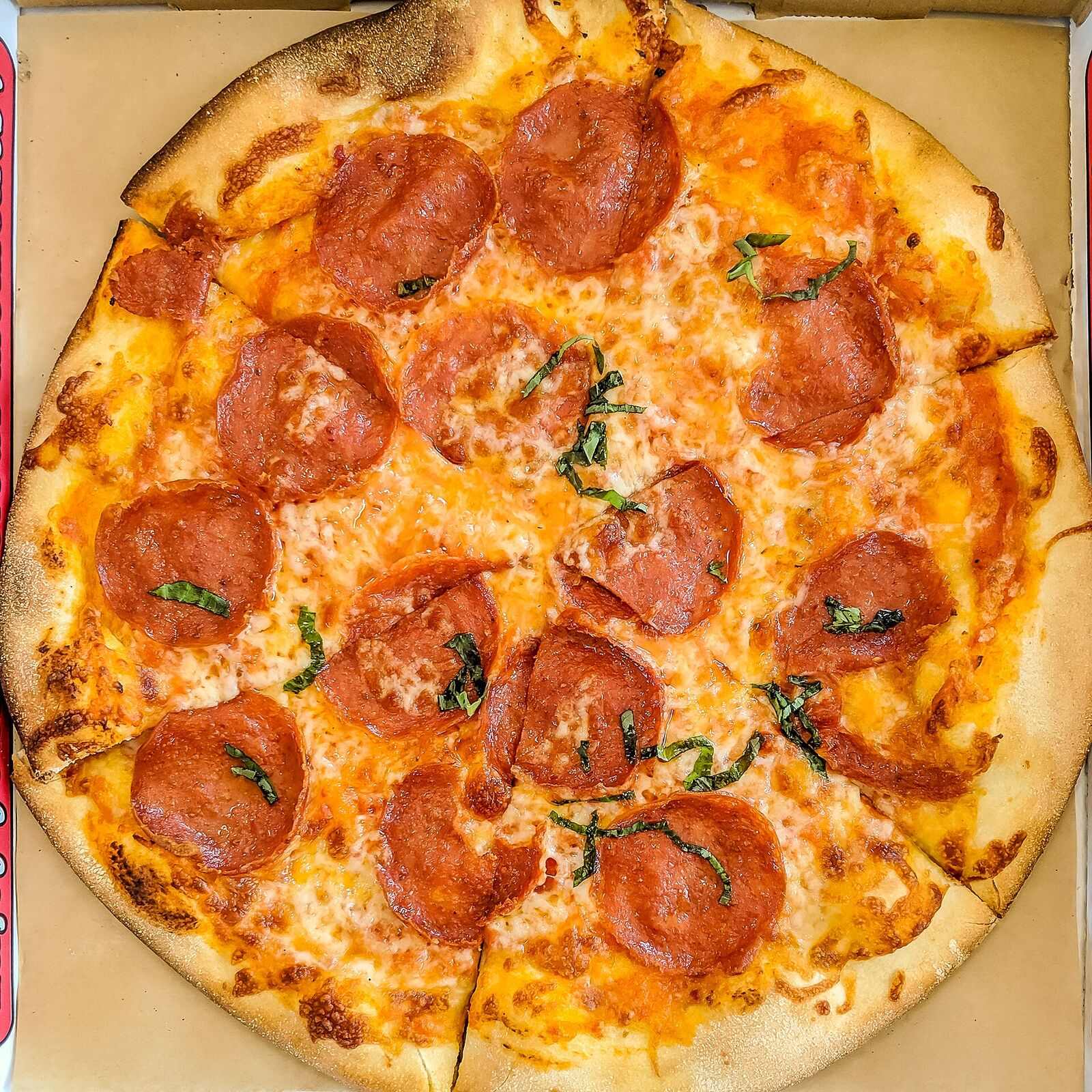 Whole pepperoni pizza seen from above, covered edge to edge in cupped pepperoni