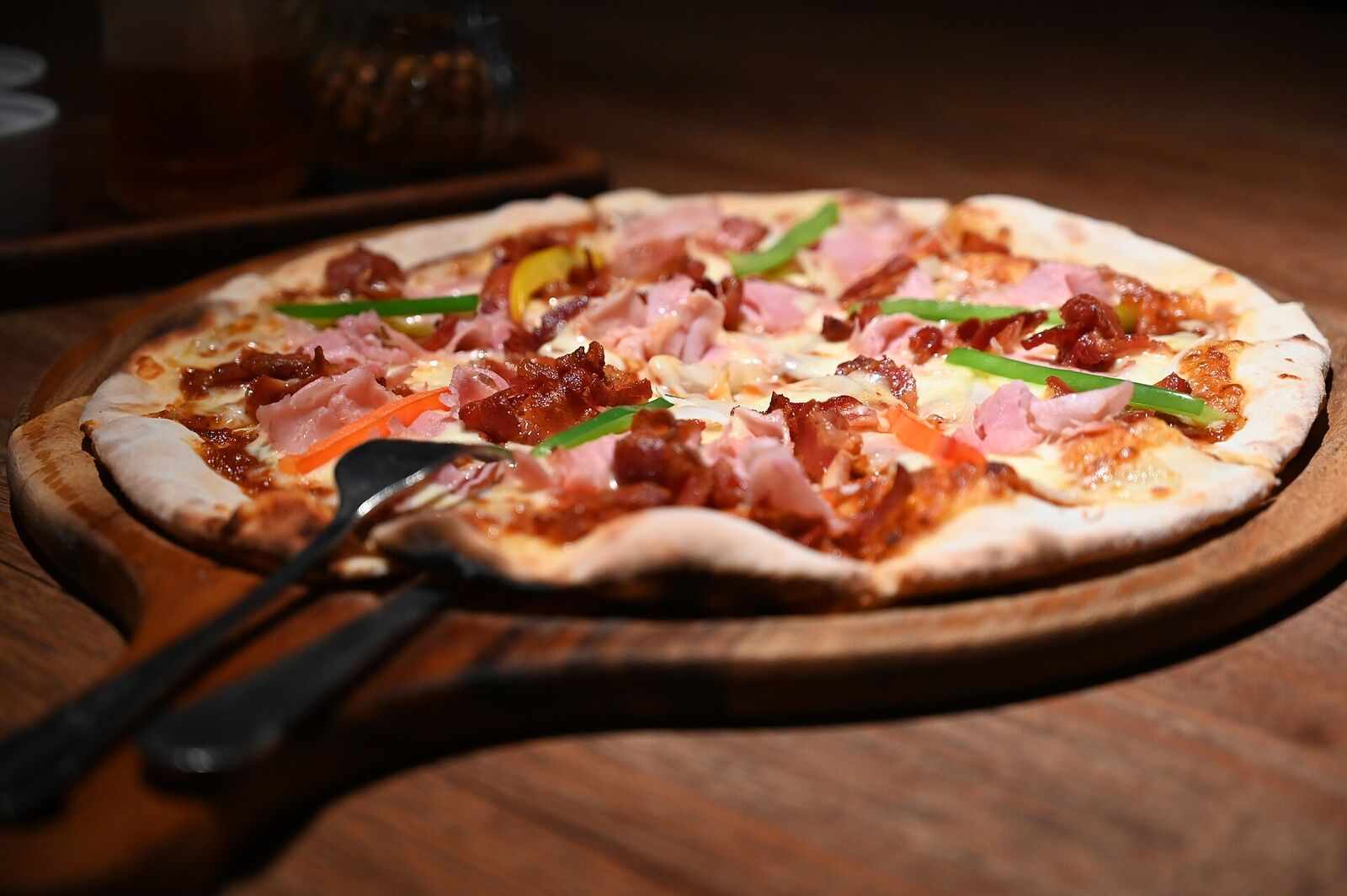 Whole pizza on a wooden board in warm light